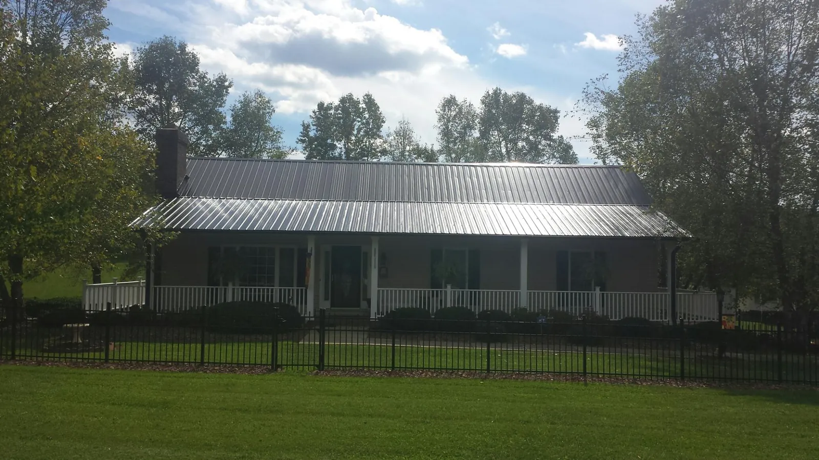 Gray metal roof on a brick ranch with a full width front porch — Gutter Guard Installation work by our crew in Paradise Valley