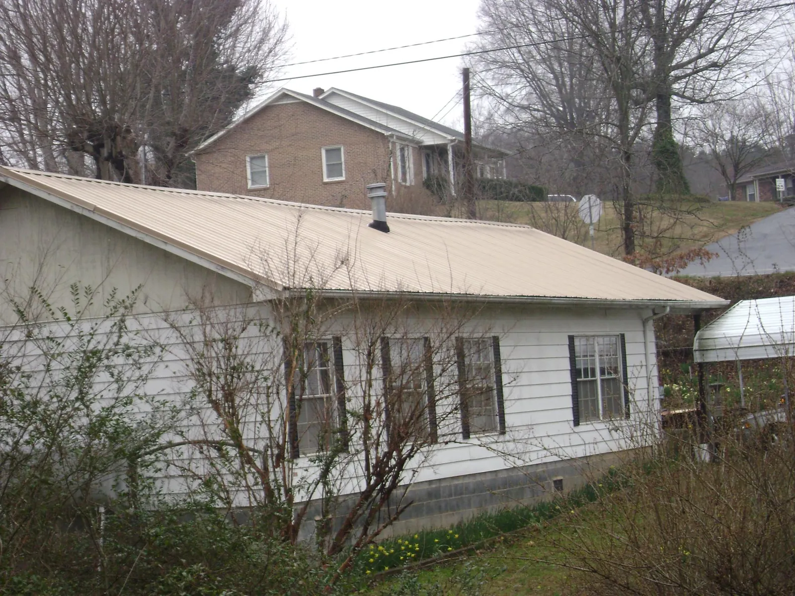 Tan metal roof on a white sided house set into a hillside — Commercial Roofing by Roofing Brothers in Paradise Valley