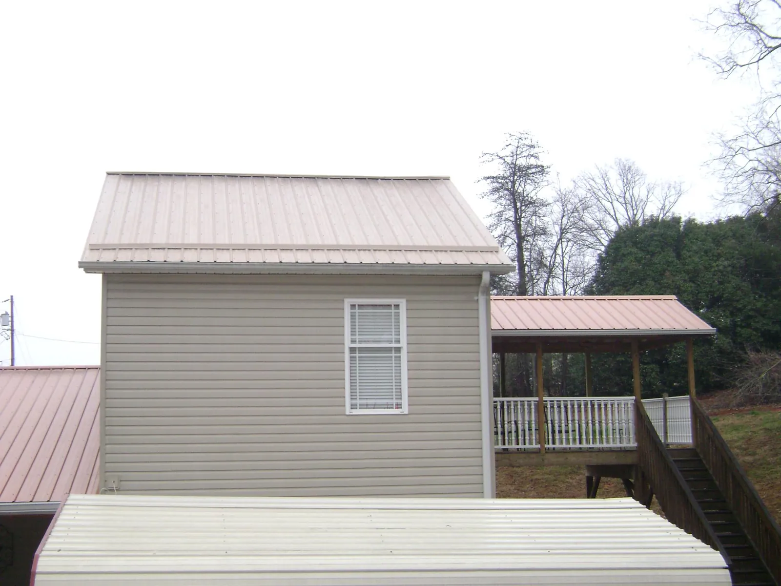 Tan metal roofs on a two story addition and attached porch, from a Roof Replacement job in Paradise Valley