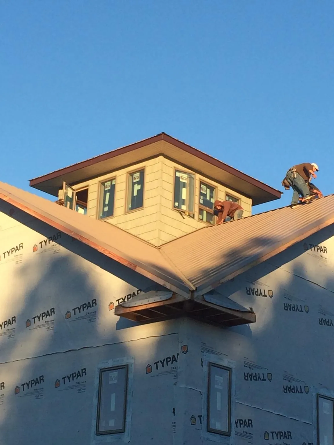 Roofers working around a rooftop cupola on a new metal roof at sunset — Roof Waterproofing in Paradise Valley by Roofing Brothers